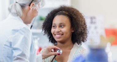 pediatrician checking teen heartbeat