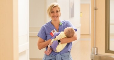 A cardiac catheterization nurse holds an infant in the Children’s Heart Center