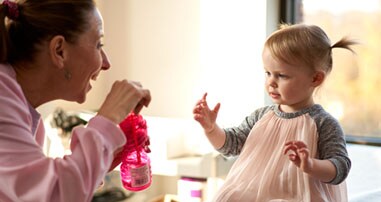 nurse blowing bubbles to girl on hospital bed