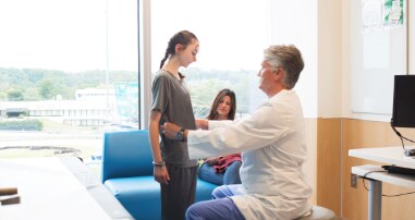 Physician testing teen with a scoliosis screening