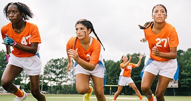 Female teen flag football players running on a field.