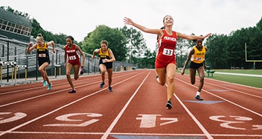 Female teen track runners in high school race.