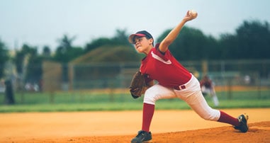 Youth baseball player pitches in baseball game.