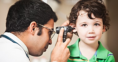 Otolaryngologist examining child with ear tubes