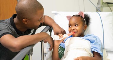 Child eating popsicle in bed post surgery