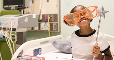 pediatric patient girl smiles with funny glasses wand and puzzle in hospital