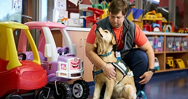 therapy dog with handler in pediatric hospital play room