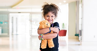 patient girl hugging teddy bear in pediatric hospital lobby