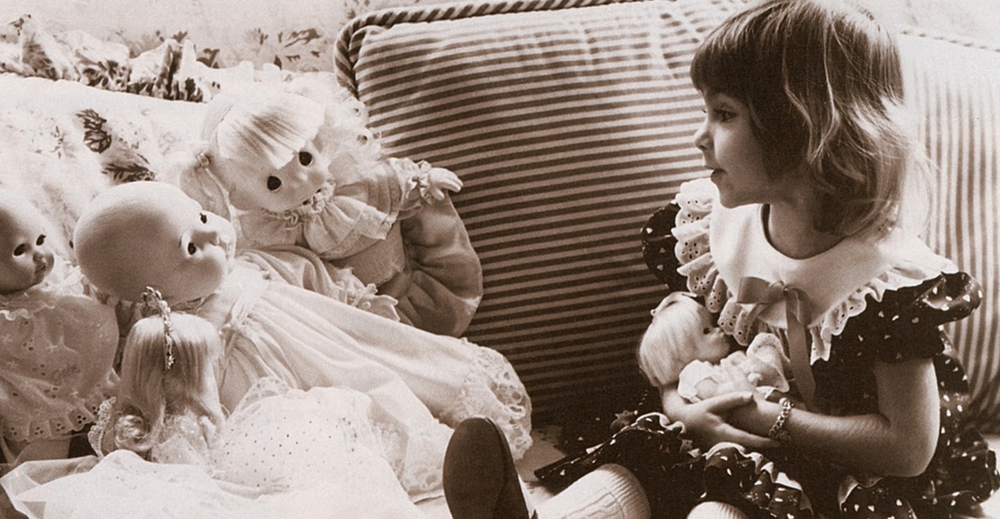 Young girl telling the history of Children's to her dolls