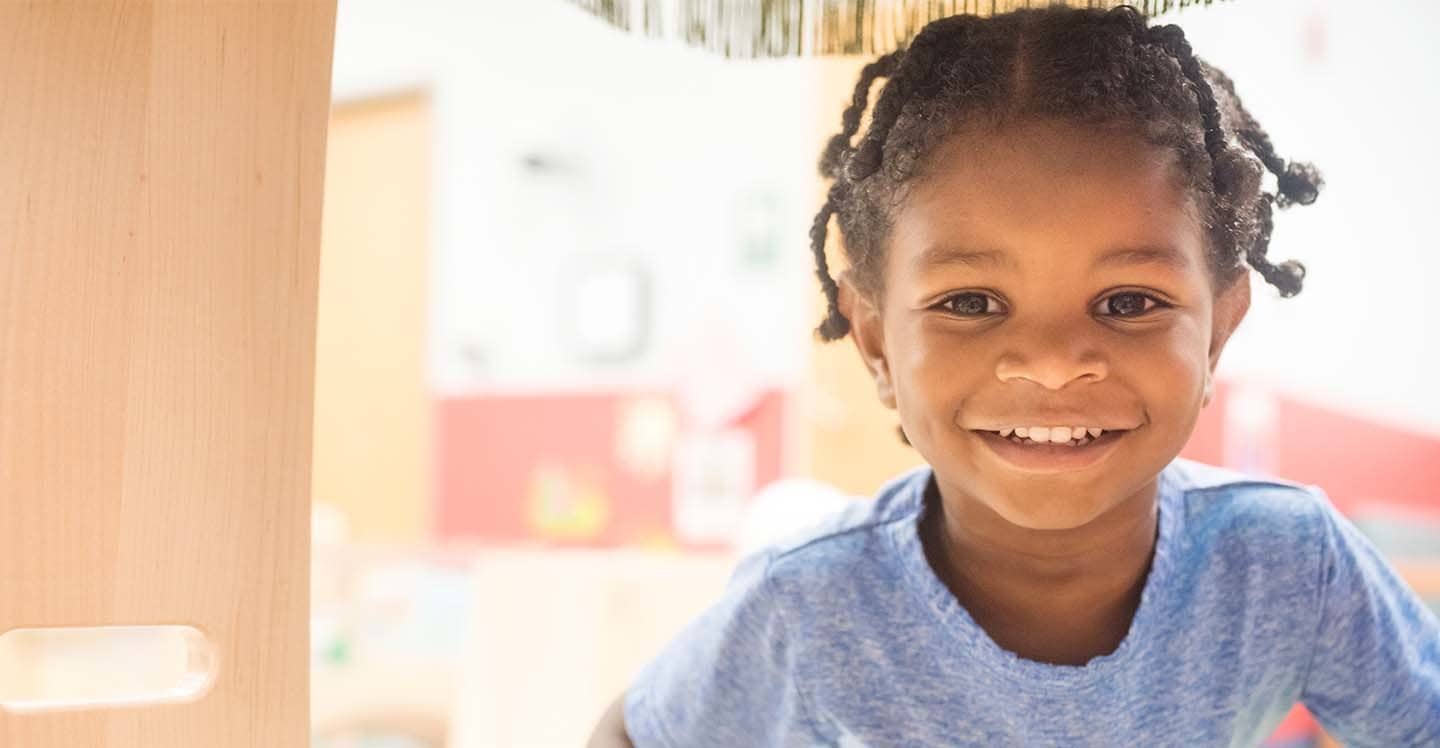 little boy smiling in preschool playground at autism center