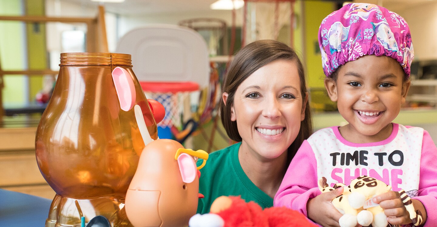 patient works with pediatric rehab therapist in rehab therapy room at pediatric hospital