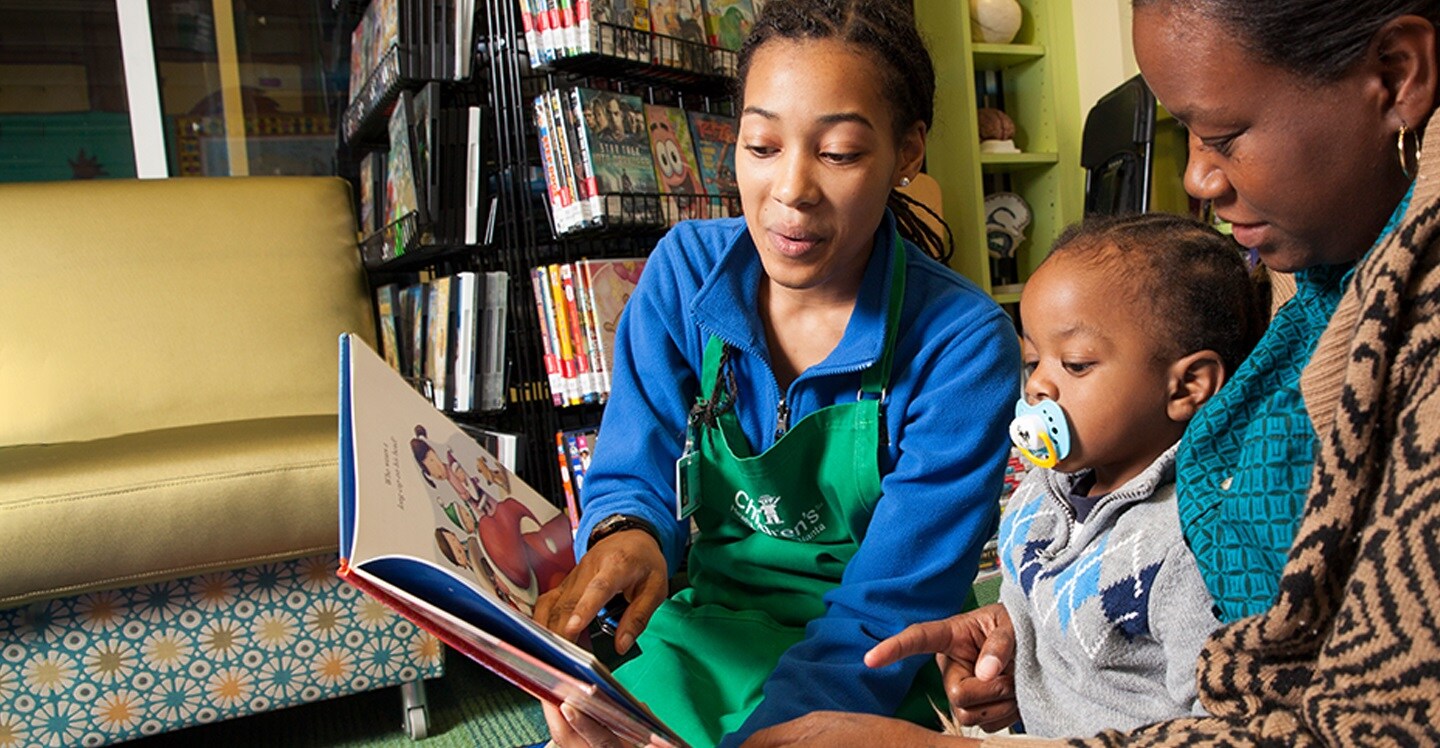 volunteer reading to patient and mom at pediatric hospital