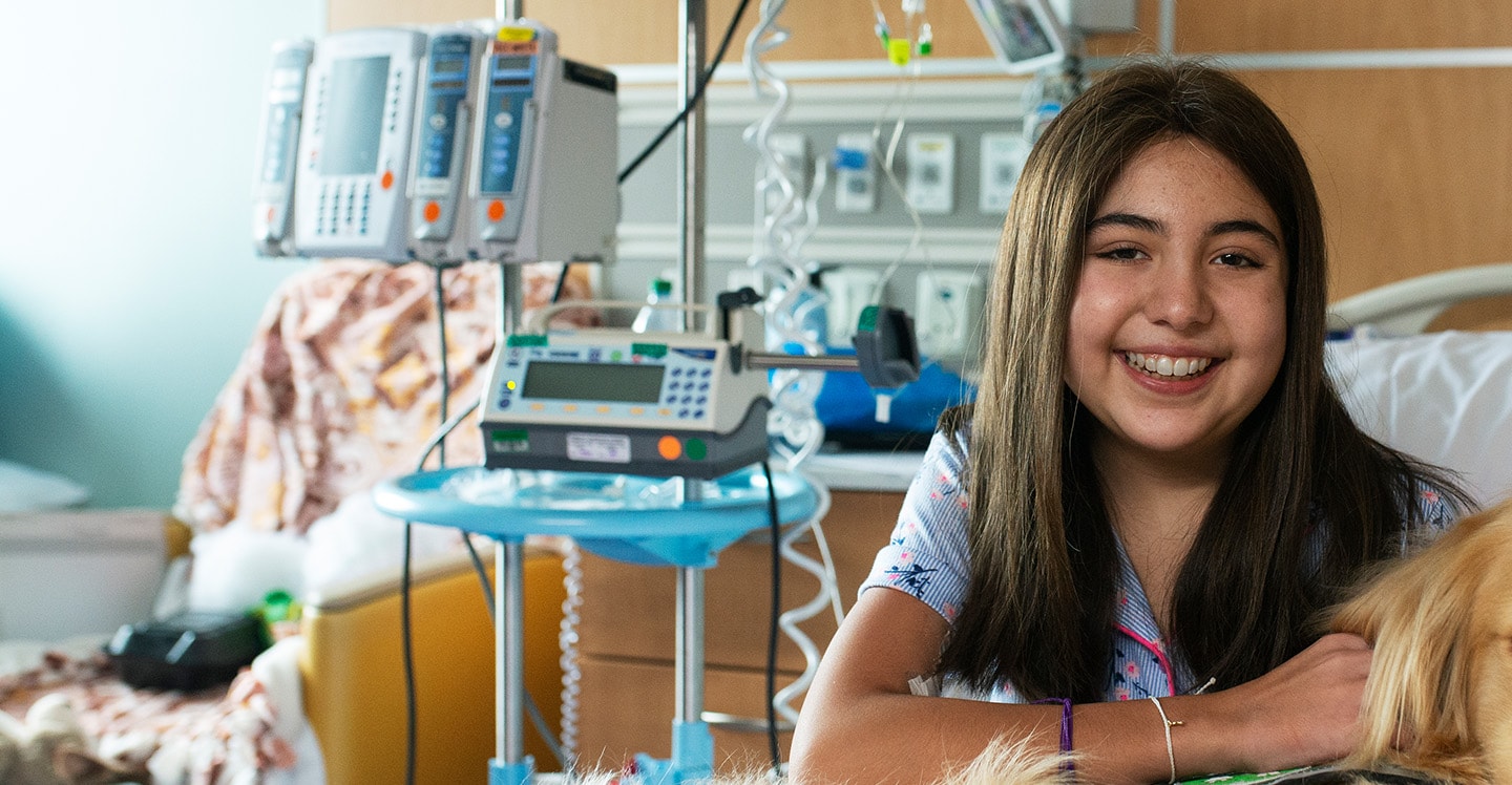 pediatric patient smiling in hospital room with facility dog