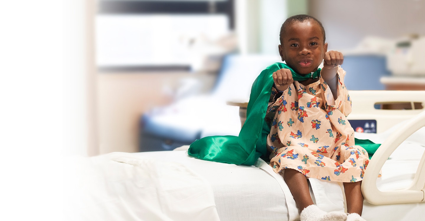 Child with cape on sitting in hospital