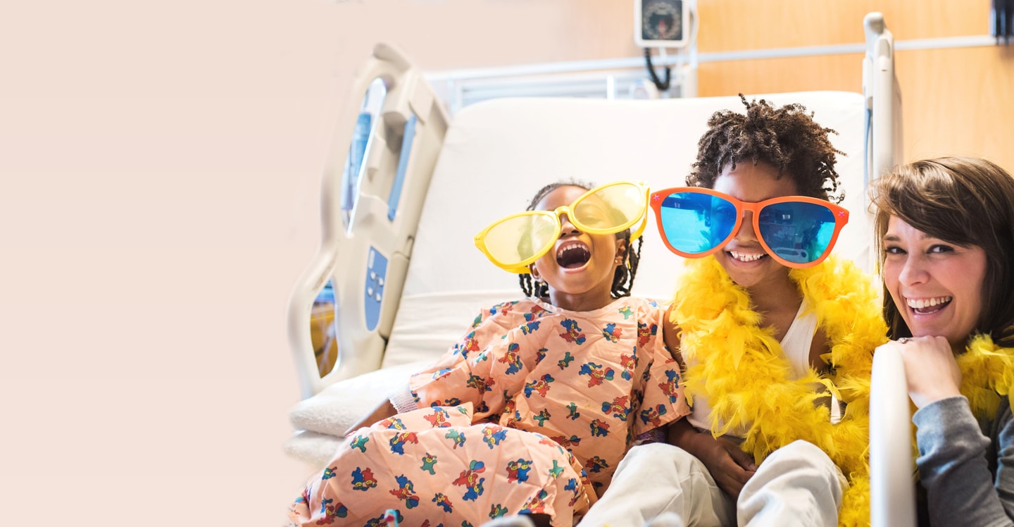 Children smiling in bed with nurse
