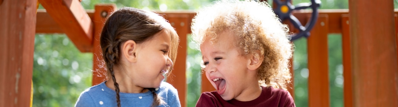 little boy and girl laughing on outdoor playset