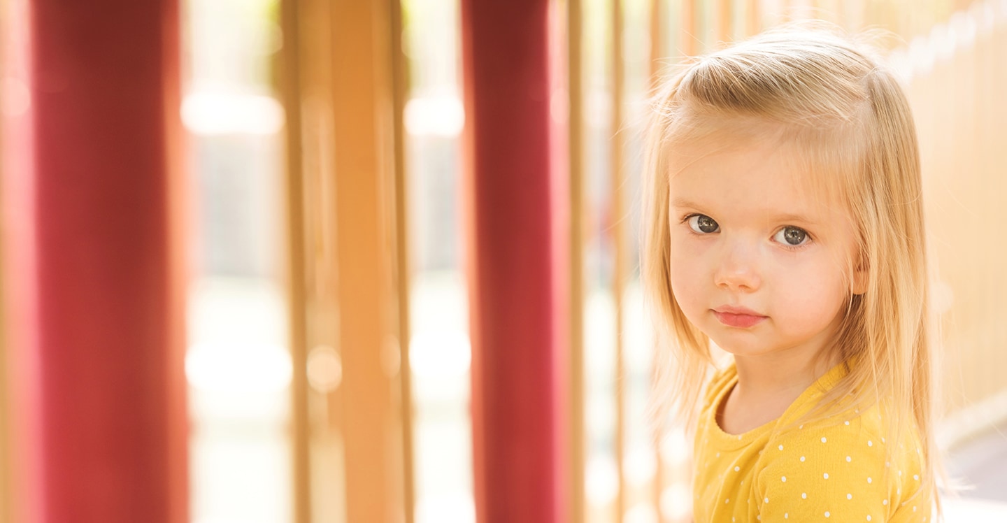 Little girl smiles before going down the slide on playground