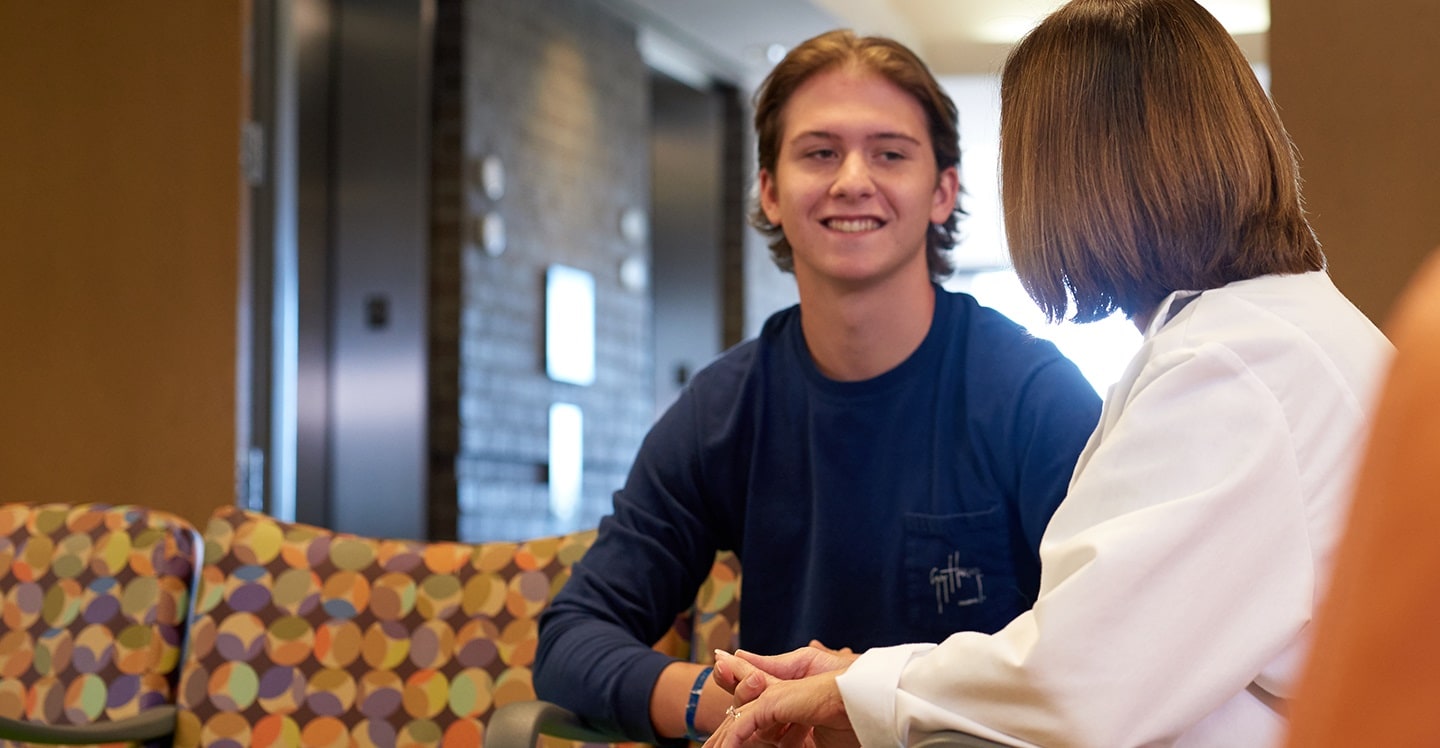 Children’s provider talking with male teen patient