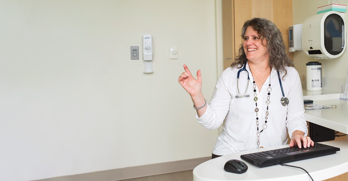pulmonologist in lab coat smiling at desk 