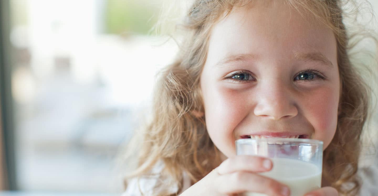 Girl smiling holding a glass of milk