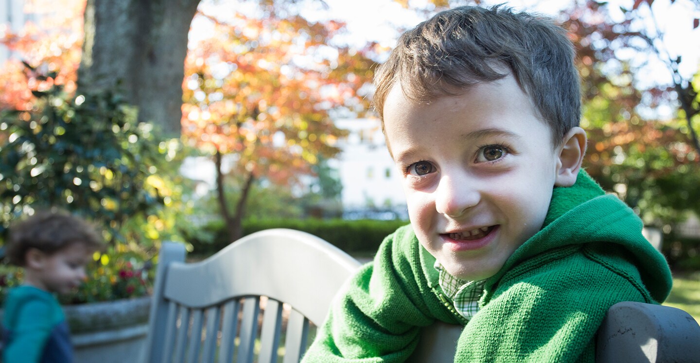 A young heart patient stands outside in a garden