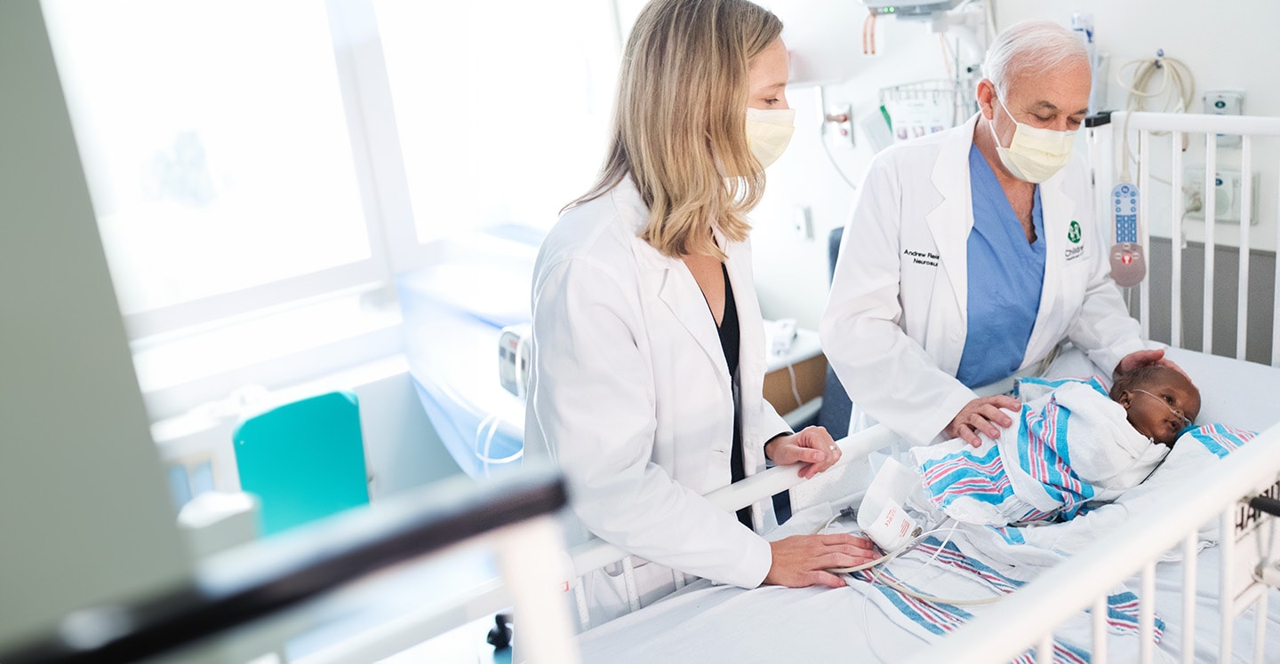 infant in crib with breathing tube with 2 doctors