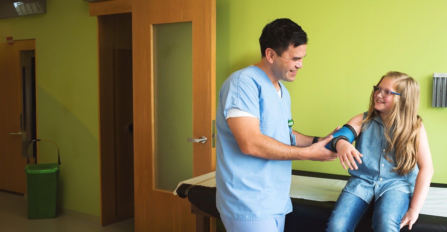 Nurse examines patient's broken arm in clinic.