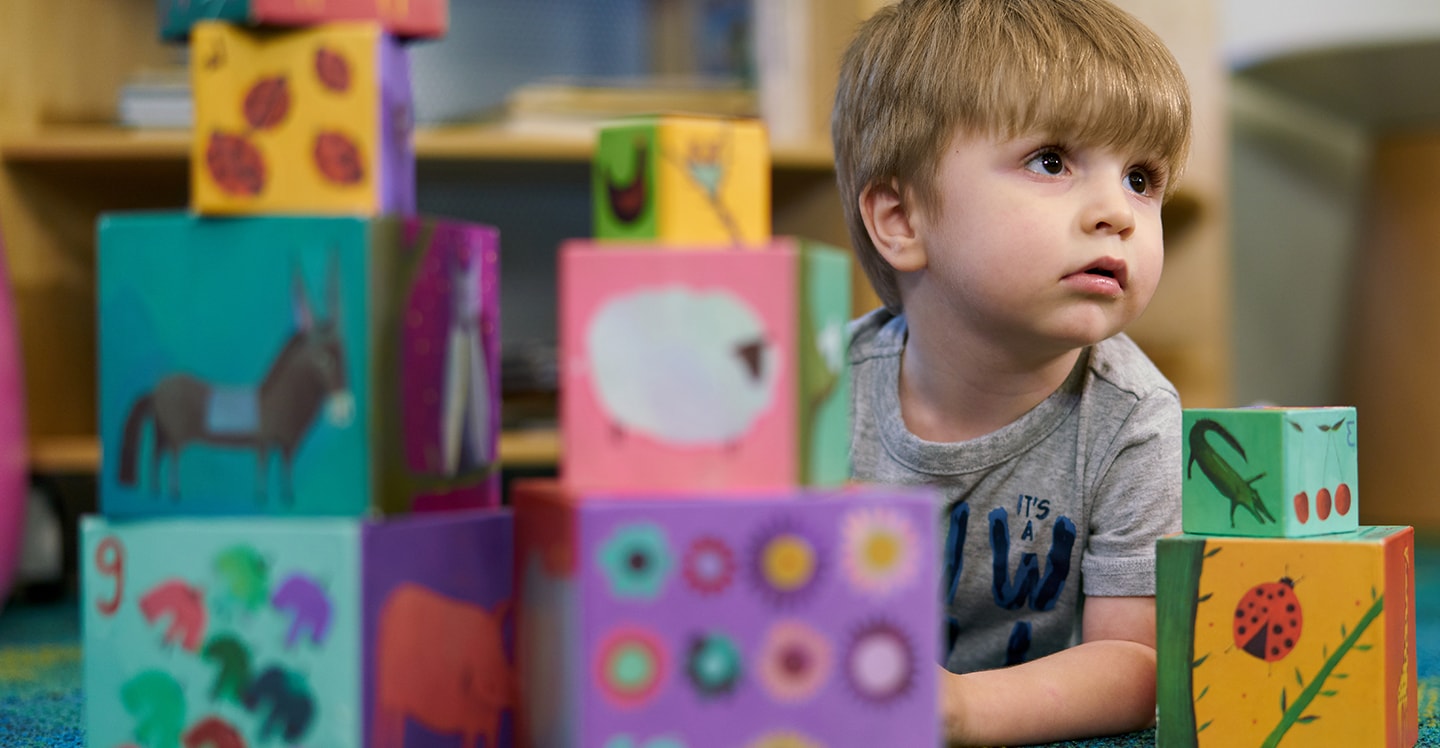 Little boy playing with building blocks at preschool