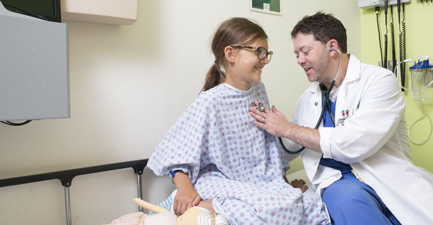 Doctor checking female patient's heartbeat with stethoscope