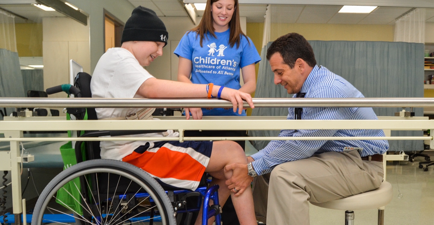 Dr. Vova, pediatric physiatrist, works with a teen rehabilitation patient in a gym