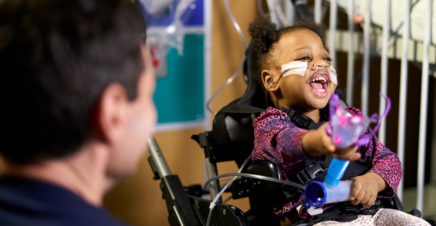 Pediatric girl patient laughing in wheelchair in inpatient rehabilitation.