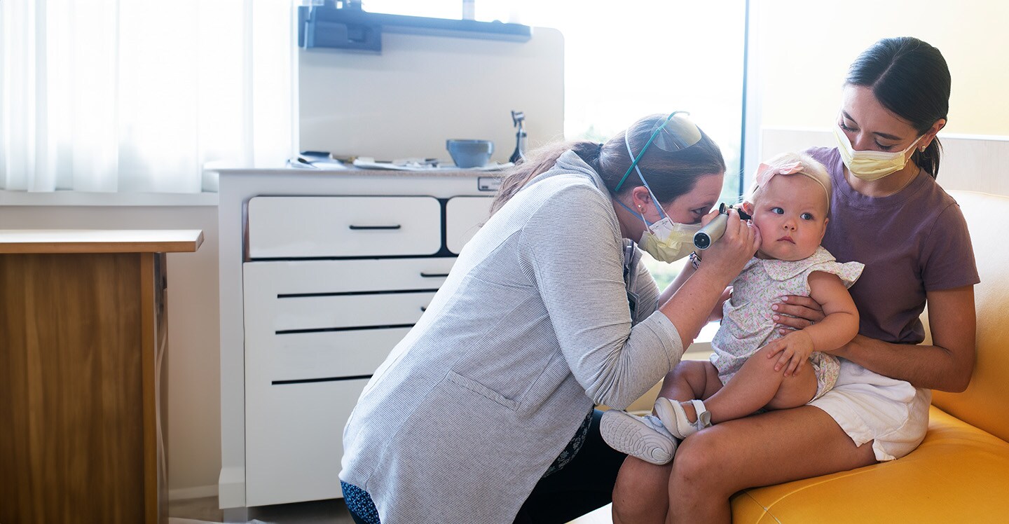 Dr. Alfonso looks into baby's ear during ENT appointment.