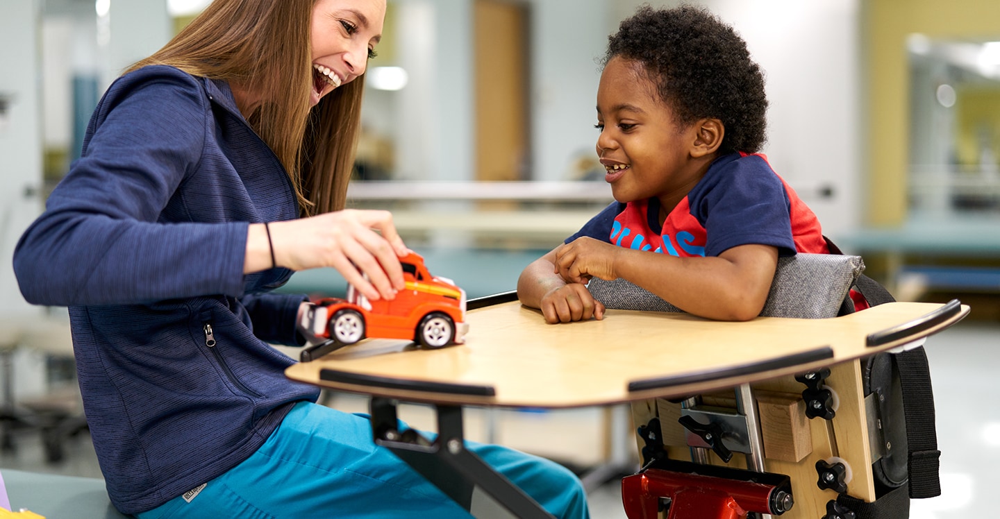 Therapist uses toys to work with patient boy in pediatric rehab