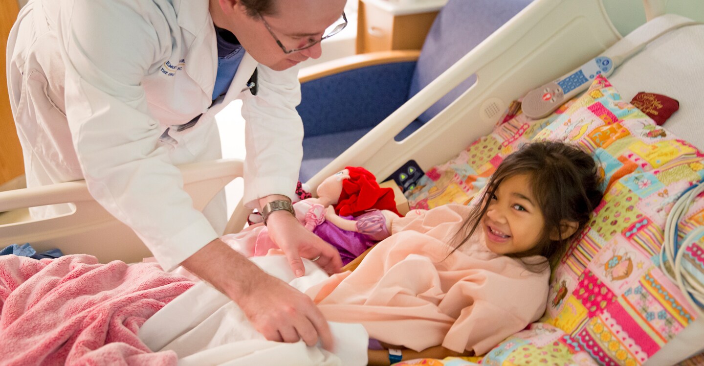 doctor checking on girl in hospital bed