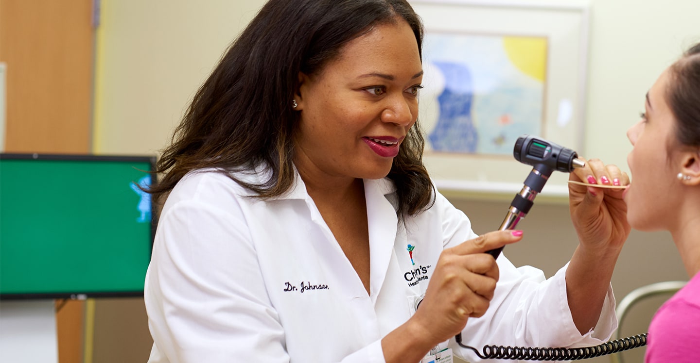 Doctor examines patient girl’s throat in urgent care center