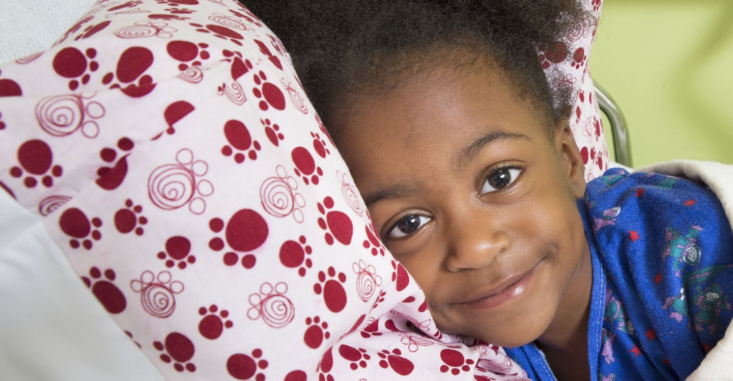 Little girl smiling in hospital bed 