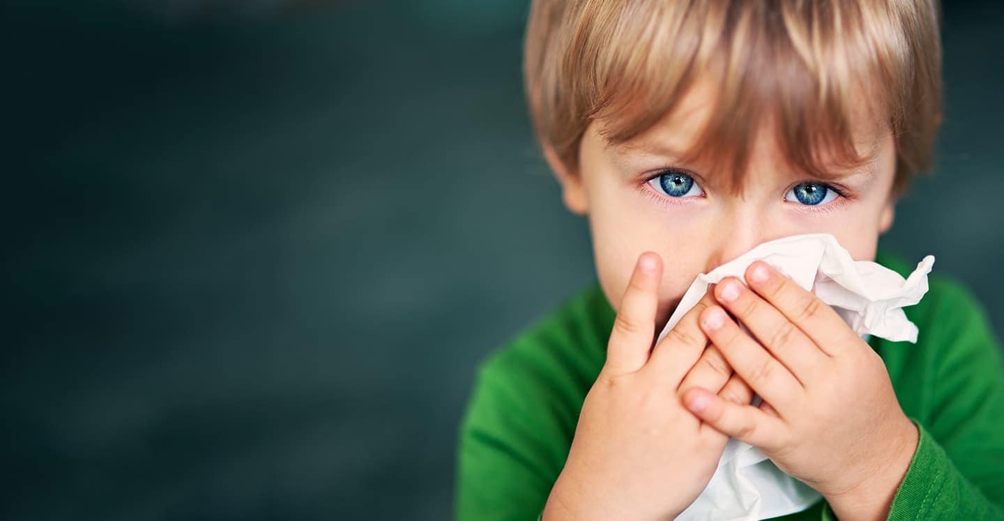 child with allergies blowing their nose