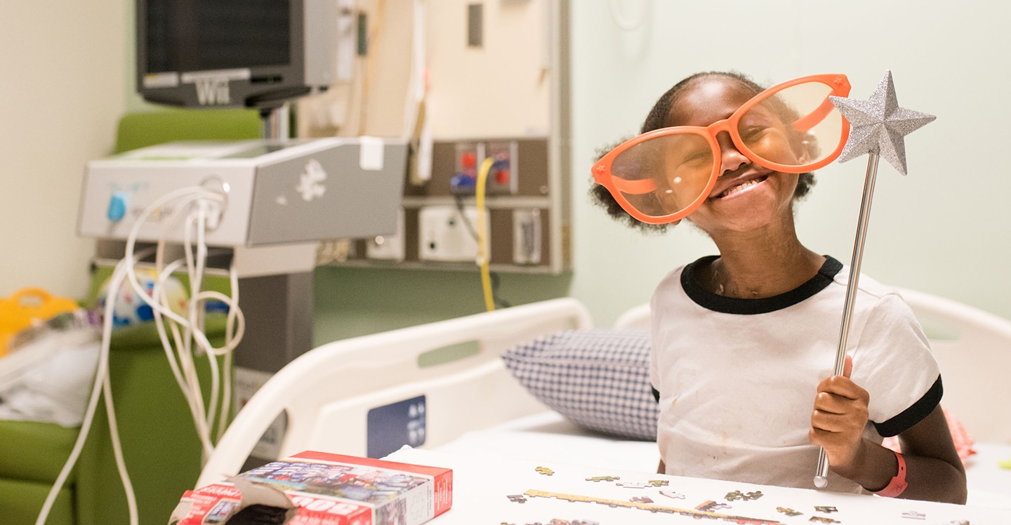 pediatric patient girl smiles with funny glasses wand and puzzle in hospital
