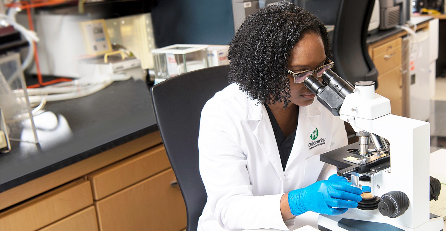 researcher looking into microscope