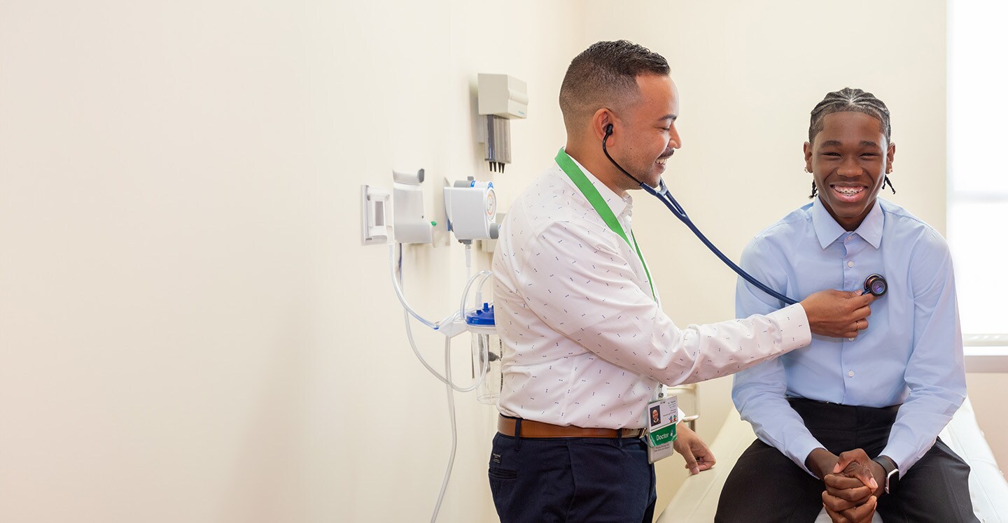 doctor using stethoscope on teen boy patient