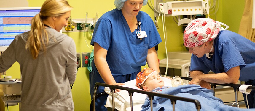 Boy in post-anesthesia care unit with doctors and nurses after surgery.