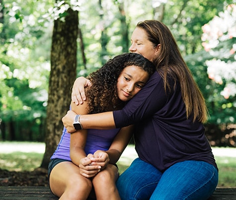 Mom hugging teen daughter