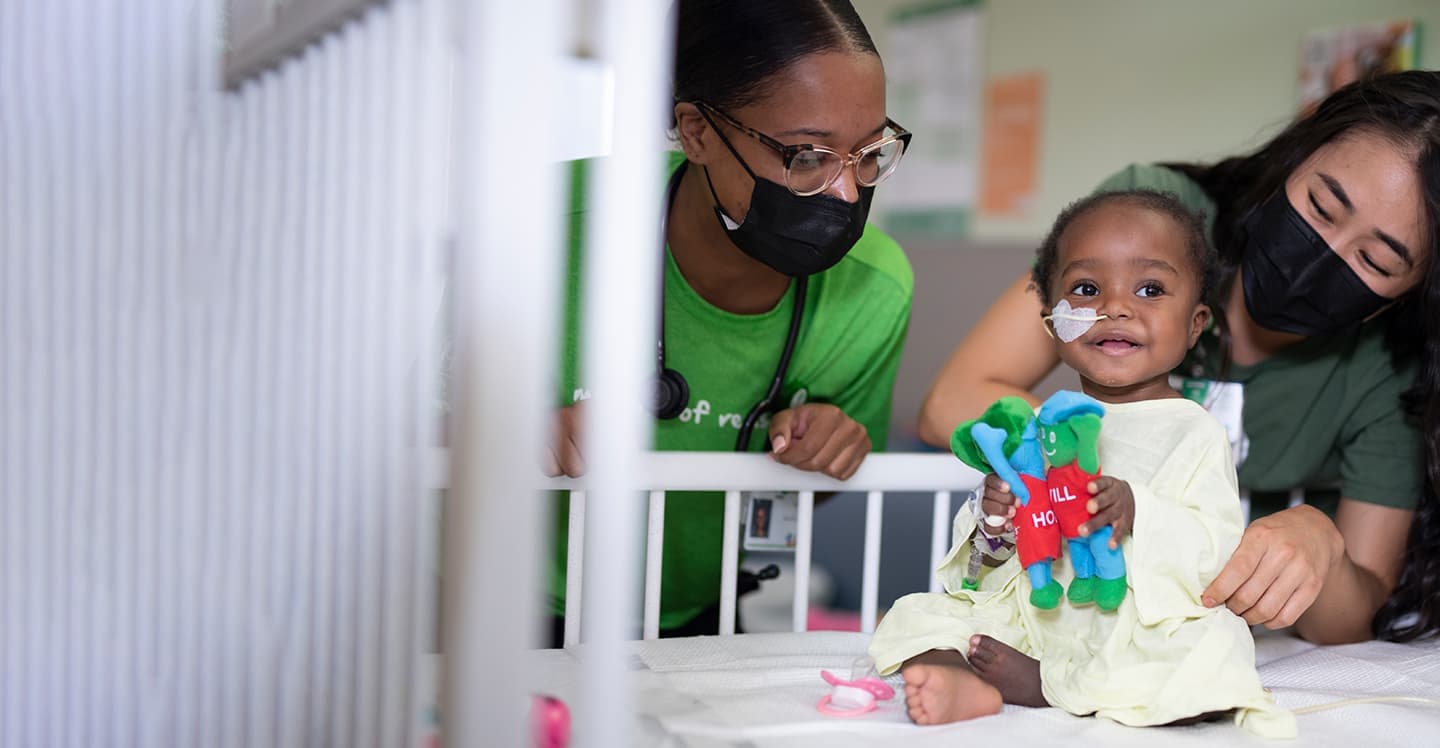 Nurses with baby in hospital bed