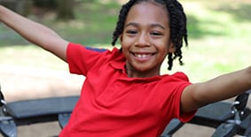 Boy in red shirt outside on swing