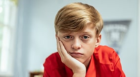 Teen boy sitting at desk looking sad and disinterested 
