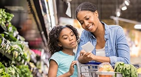 Teen girl and mom look at grocery list in grocery store