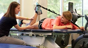 Sports physical therapist performing functional testing on teen patient