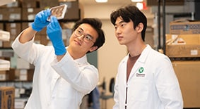 two researchers in white lab coats looking at slide