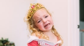 toddler girl crying while wearing princess dress and crown