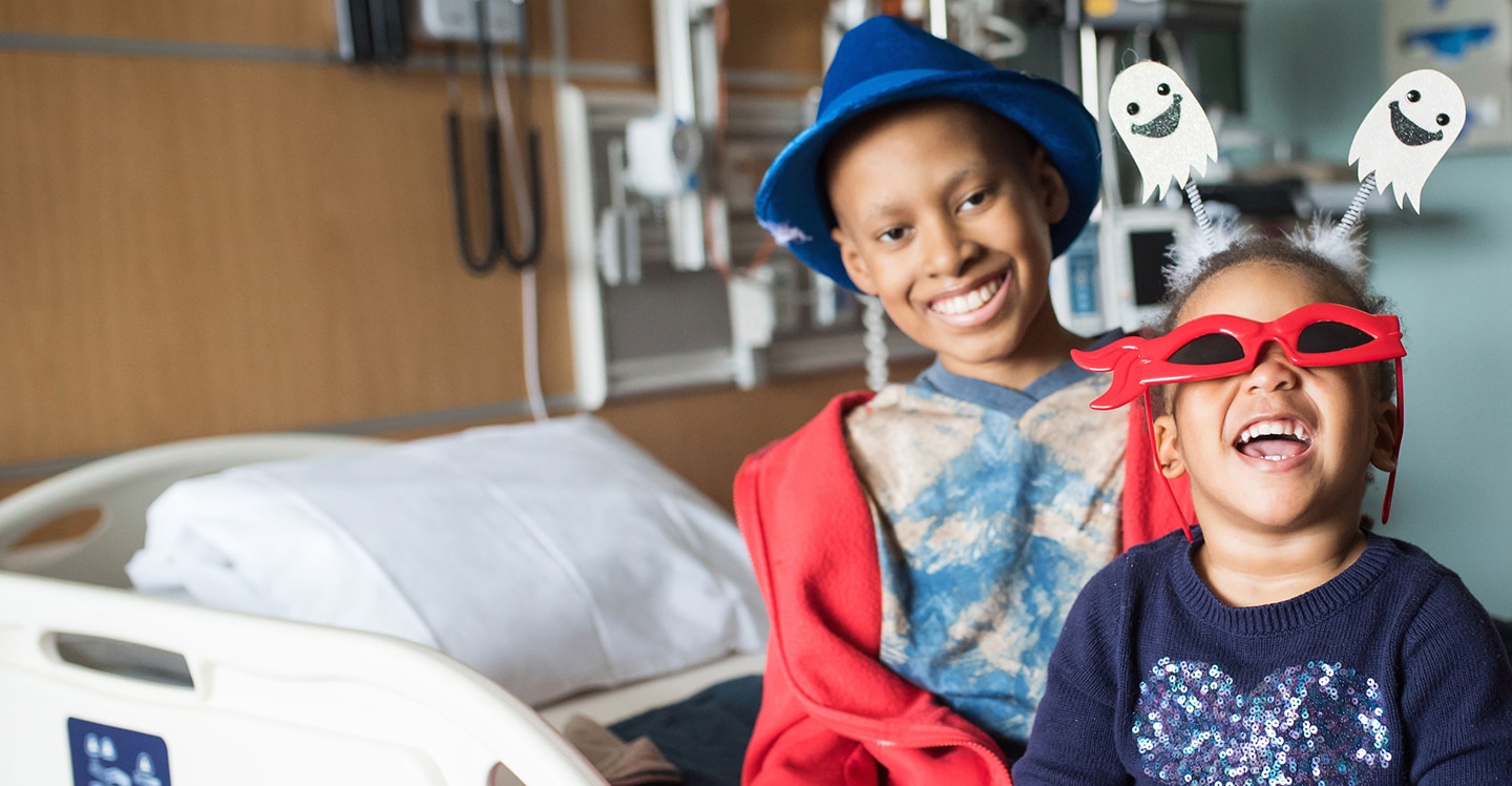 Young cancer patient playing dress-up with younger sister.